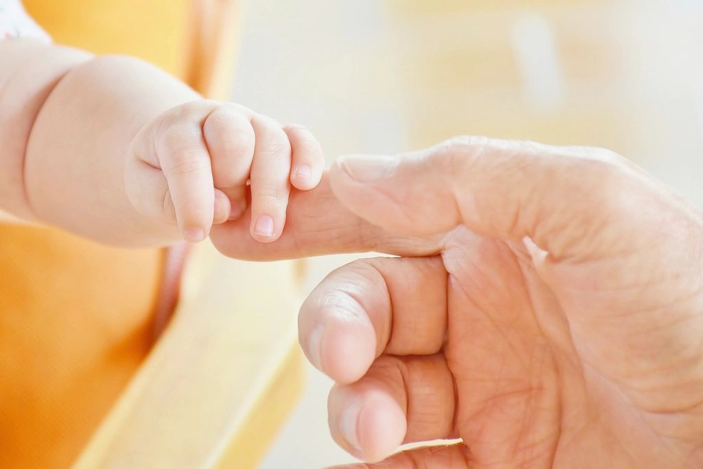 Mano de un bebé agarrando el dedo de su padre